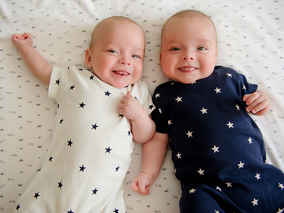 Bliźniaki – niemowlęta leżące obok siebie w podobnych body w gwiazdki